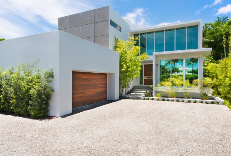 a white boxy garage in front of a beach-front contemporary house