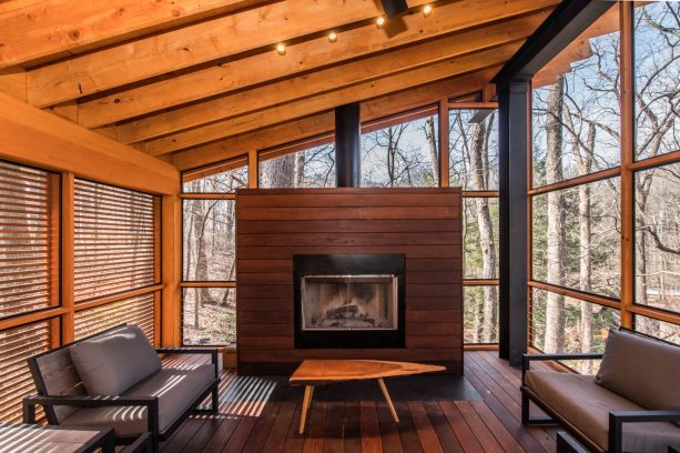 an industrial screened porch looks very stylish with wood materials and fireplace