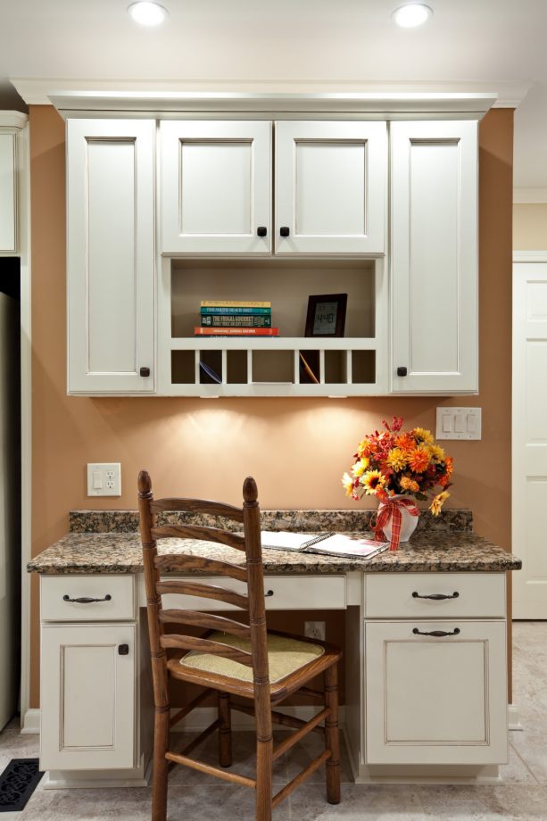 a kitchen desk cabinet with glaze, white color, and brown granite countertops