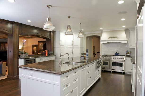 a kitchen looks clean because of the clean white cabinets, silver colors, and brown granite combo