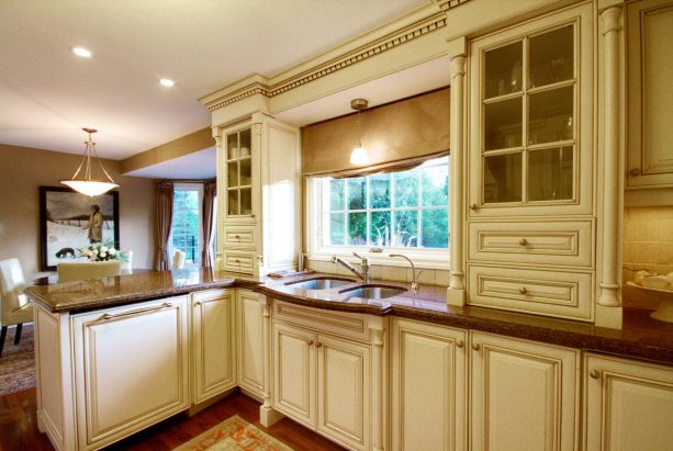 a traditional kitchen looks elegant and luxurious with cream white cabinets, crown molding, and brown granite countertops