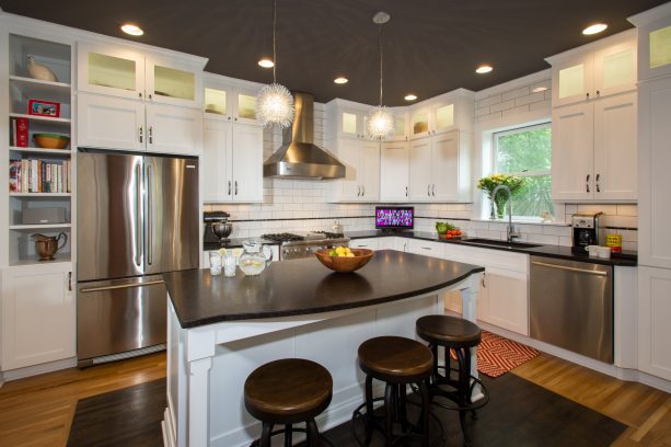 a traditional kitchen with stainless-steel appliances, white cabinets, and leathered-finish brown granite countertops