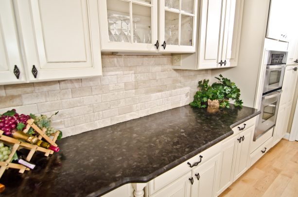 an antique white kitchen cabinets with leathered brown granite countertop