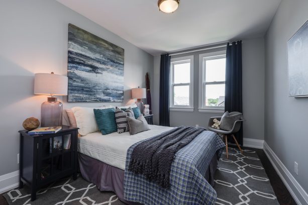 a black and grey contemporary bedroom with accentuating teal pillows