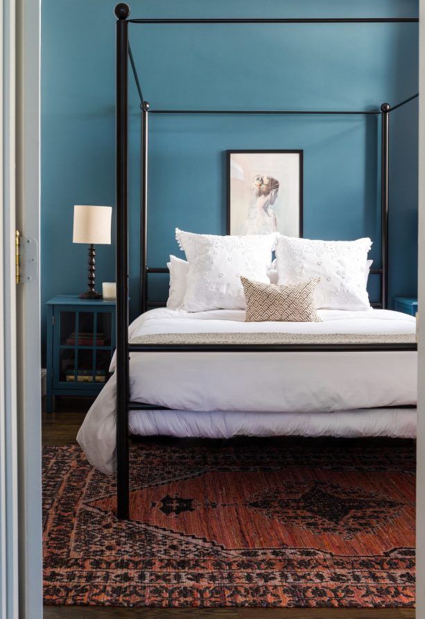 a black traditional canopy bed in a teal transitional bedroom design