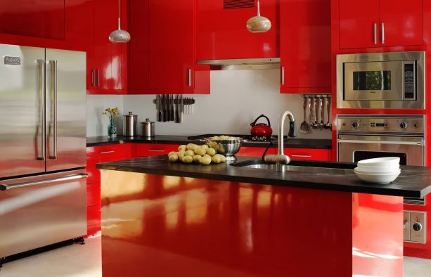 a contemporary kitchen with glossy red cabinets and island, black cabinets, and white backsplash