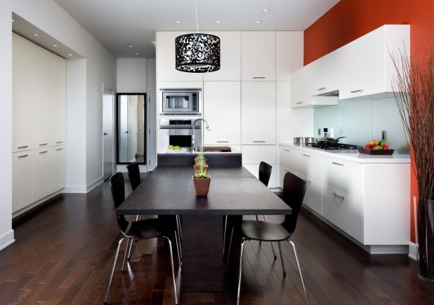 a contemporary kitchen with stunning red accent, white cabinets, and black table set