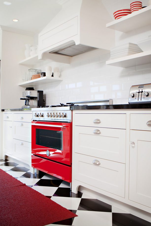 a dominant white color in a traditional kitchen with red range and black countertops