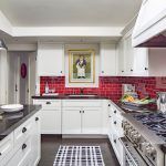 a red subway tile backsplash looks stunning in a black and white transitional kitchen interior