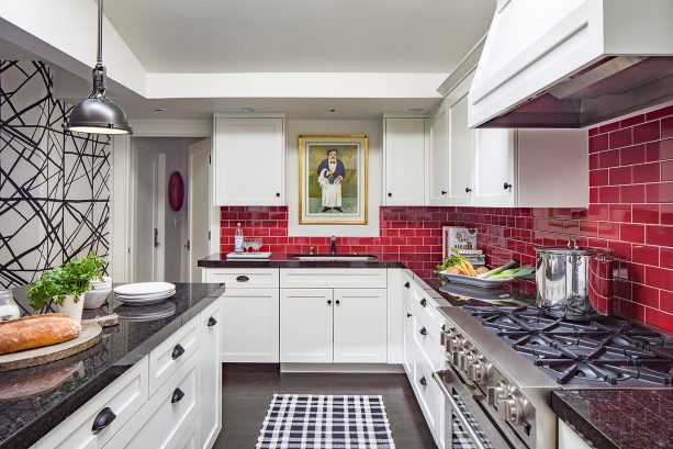 a red subway tile backsplash looks stunning in a black and white transitional kitchen interior