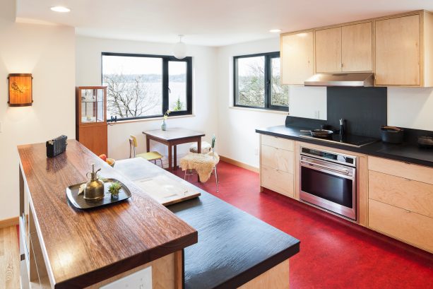 a stunning red flooring in a black and white kitchen completed with wood cabinets