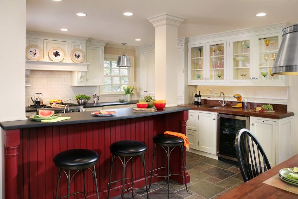 a traditional warm white kitchen with boldly elegant red island with black countertop
