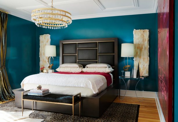 a transitional bedroom with elegant and bold teal walls, black headboard, and gold accents here and there