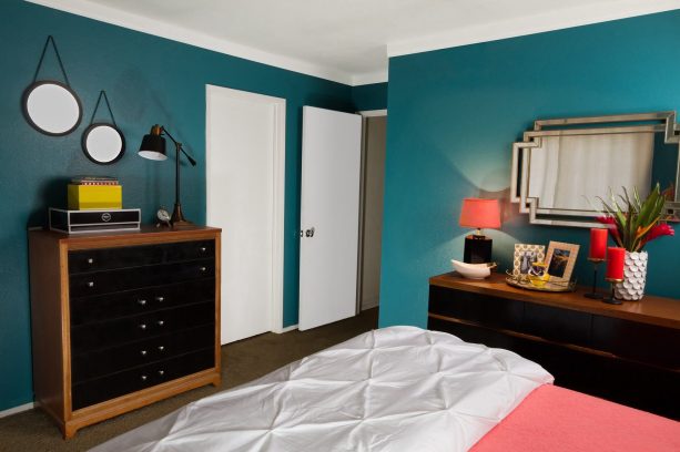 black bedroom furniture with wood accents in front of teal walls