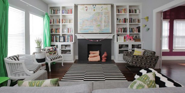 a brick fireplace in black surrounded by two white bookshelves in a classic, eclectic living room