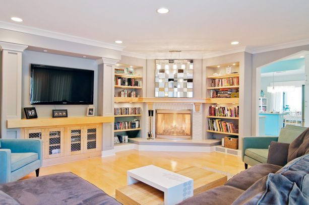 a fireplace and a pair of bookshelves uniquely located in the corner of a contemporary family room