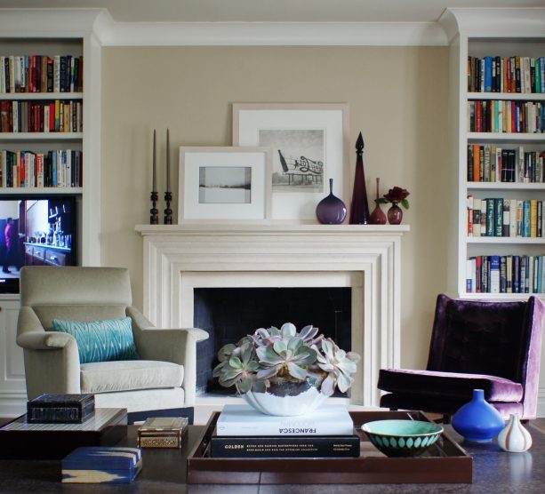 a pair of built-in bookshelves with crown molding at the top matched with a traditional fireplace in antique white