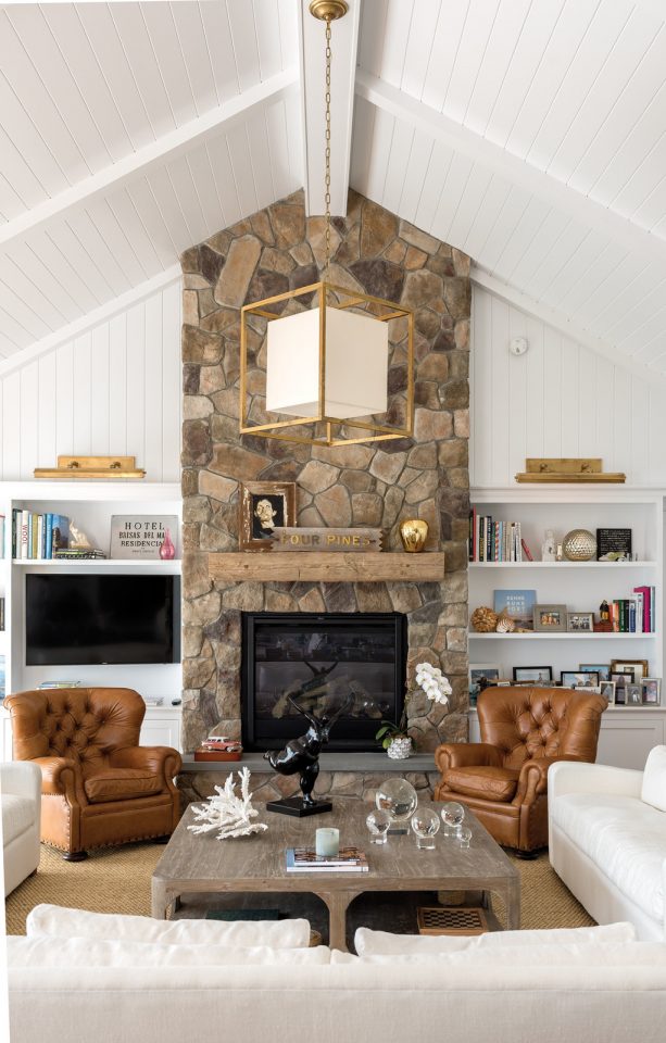 a wall height stone fireplace with white bookshelves that function also for placing a wall-mounted TV