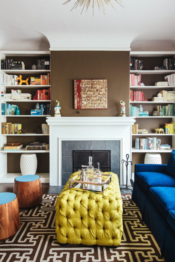 a white fireplace matched with simple yet unique bookshelves with brown wall as the back panels