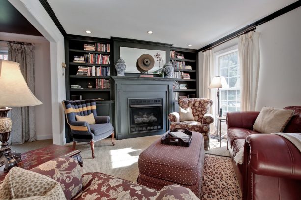 grey fireplace with black bookshelves in a traditional living room with reddish brown furniture pieces