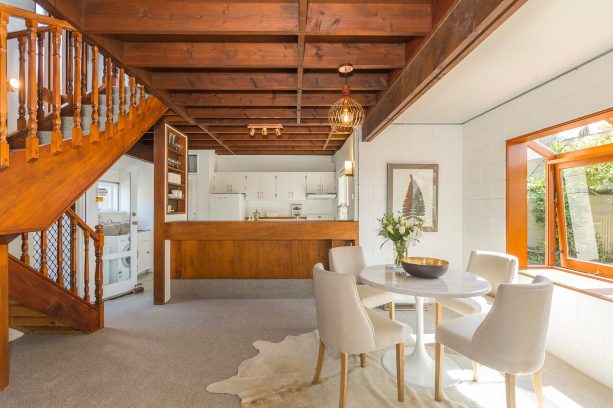 an open kitchen and dining room with white-painted cinder block walls and stained-wood elements