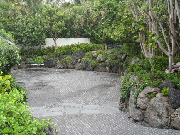 Asian-style driveway landscape with black lava rock retaining wall