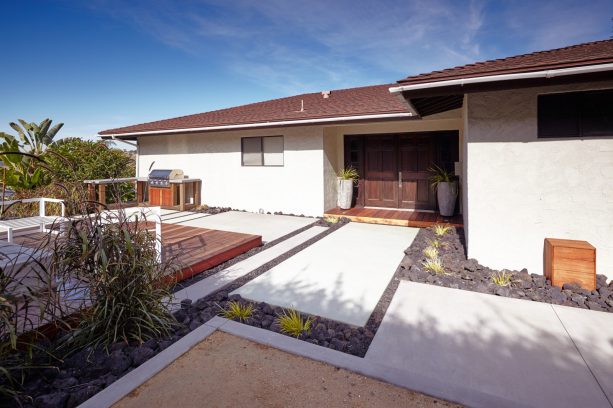 a modern landscape with larger black lava rocks between the concrete pavers