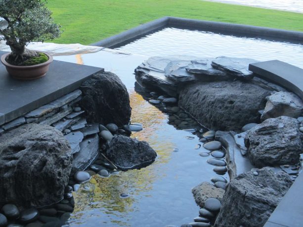 a water feature in a contemporary landscape design made from black lava boulders