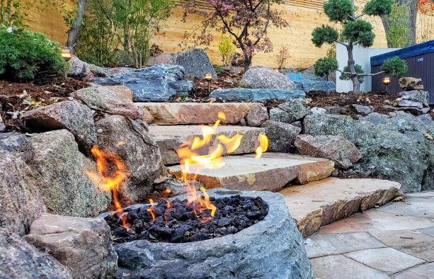 a zen garden landscape complete with fire pit and black lava rock inside it