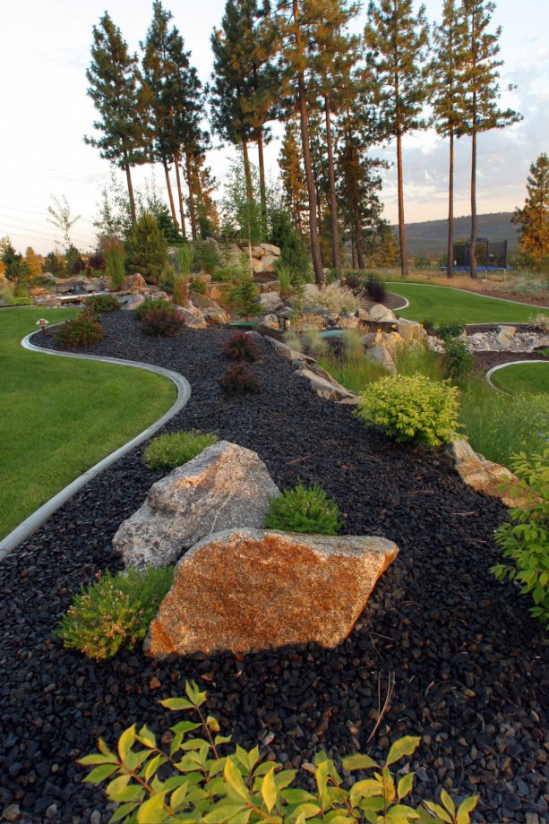 the pairing of boulders and black lava rocks in a grassy, contemporary landscape