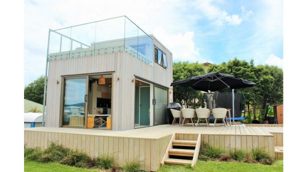 a raised-platform tiny house completed with a roof deck with glass railing