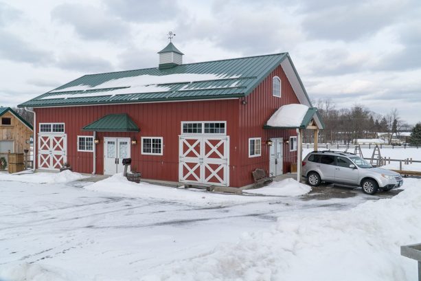 the commercial pole barn exterior looks gorgeous with the combination of red walls and a green roof