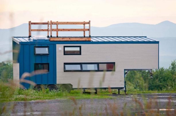 the roof deck with wooden rail shown in the ceiling area of a two-tone tiny house on wheels