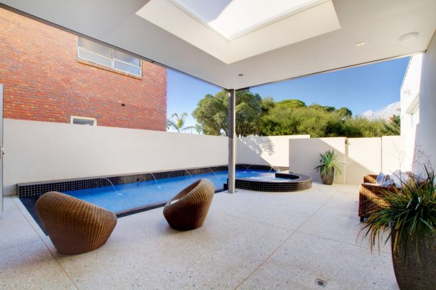 a contemporary pool patio looks trendy with its color theme, frosted-skylight, and light exposed aggregate concrete flooring