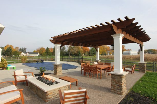 a farmhouse patio looks cozy because of the light brown exposed aggregate floor and the furniture choices
