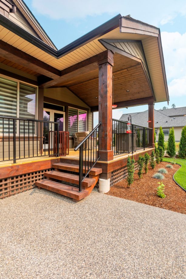 a patio with exposed aggregate concrete slab look nice being paired with beautiful landscape with brown wood mulch