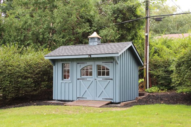 a small shed with greyish blue color and hinged garage door with double opening
