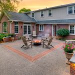 exposed aggregate-style backyard concrete patio with brick accent in the center and seatwall surrounding it