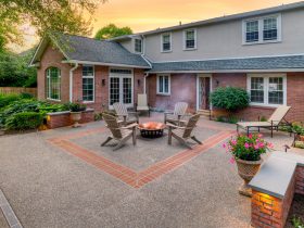exposed aggregate-style backyard concrete patio with brick accent in the center and seatwall surrounding it