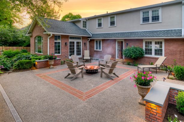 exposed aggregate-style backyard concrete patio with brick accent in the center and seatwall surrounding it