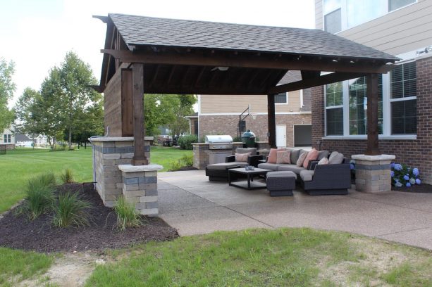 the covered patio with exposed aggregate concrete surface has TV cabinet and enough seats for everyone