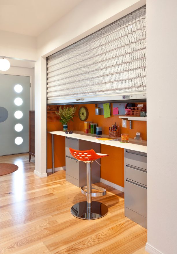 the half-opened corrugated metal roll up door of the colorful mid century home office closet