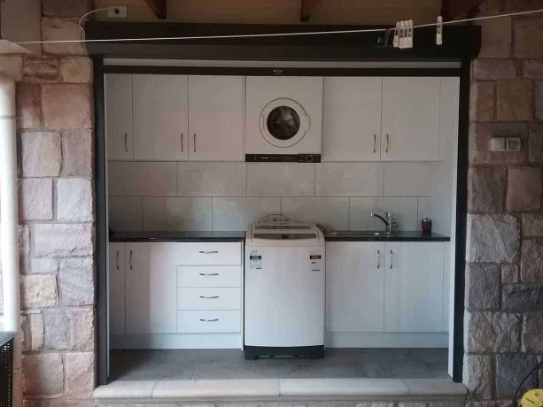 the laundry closet interior with black and white cabinetry theme shown when the rolling door is open