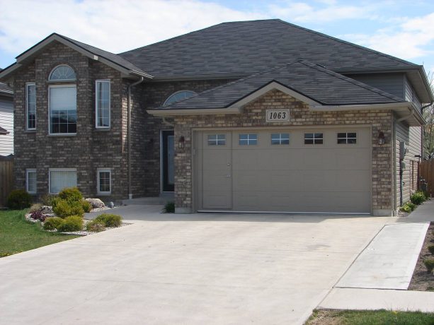 a craftsman brown brick house with beige raised panel garage door with a walkthrough