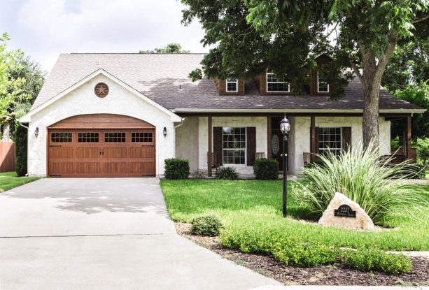 a faux wood garage door with arched top looks gorgeous in an warm white exterior