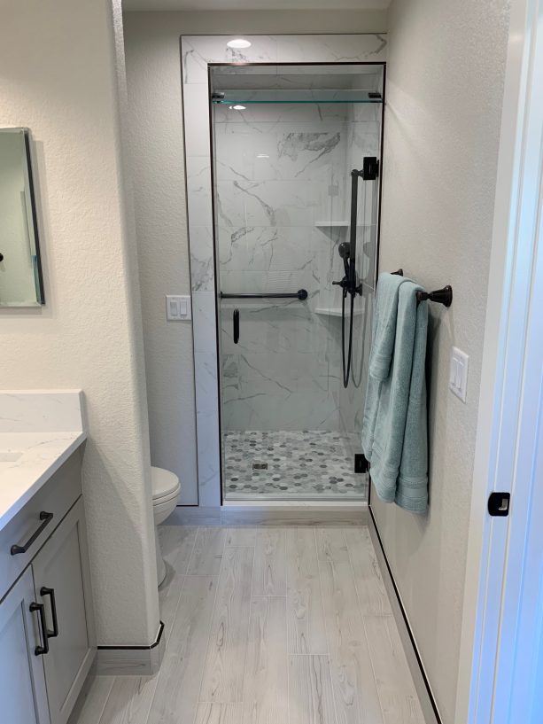 a black, white, and grey theme enclosed shower room near the toilet