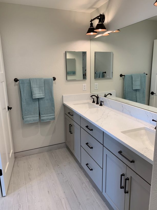 the double sink and large mirror in the narrow full bath