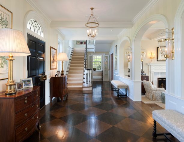 an entryway with stained diamond pattern located near another room with strip wood flooring