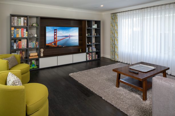 the dark wood floor in the family room looks matching with the custom entertainment center