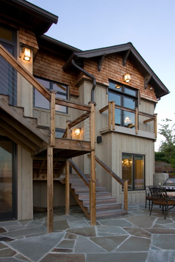 the wood and cable outdoor railing nicely matches the rustic exterior of the house